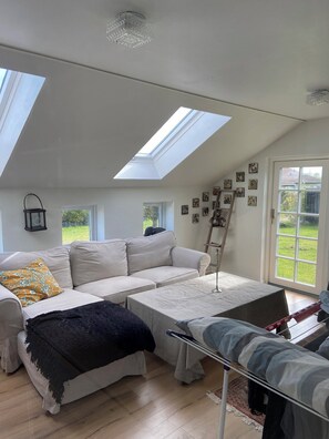 A spacious loft bedroom with skylights, a large bed, a sofa, and a dining table. - Lovely holiday home near Funens beautiful nature (Otterup)