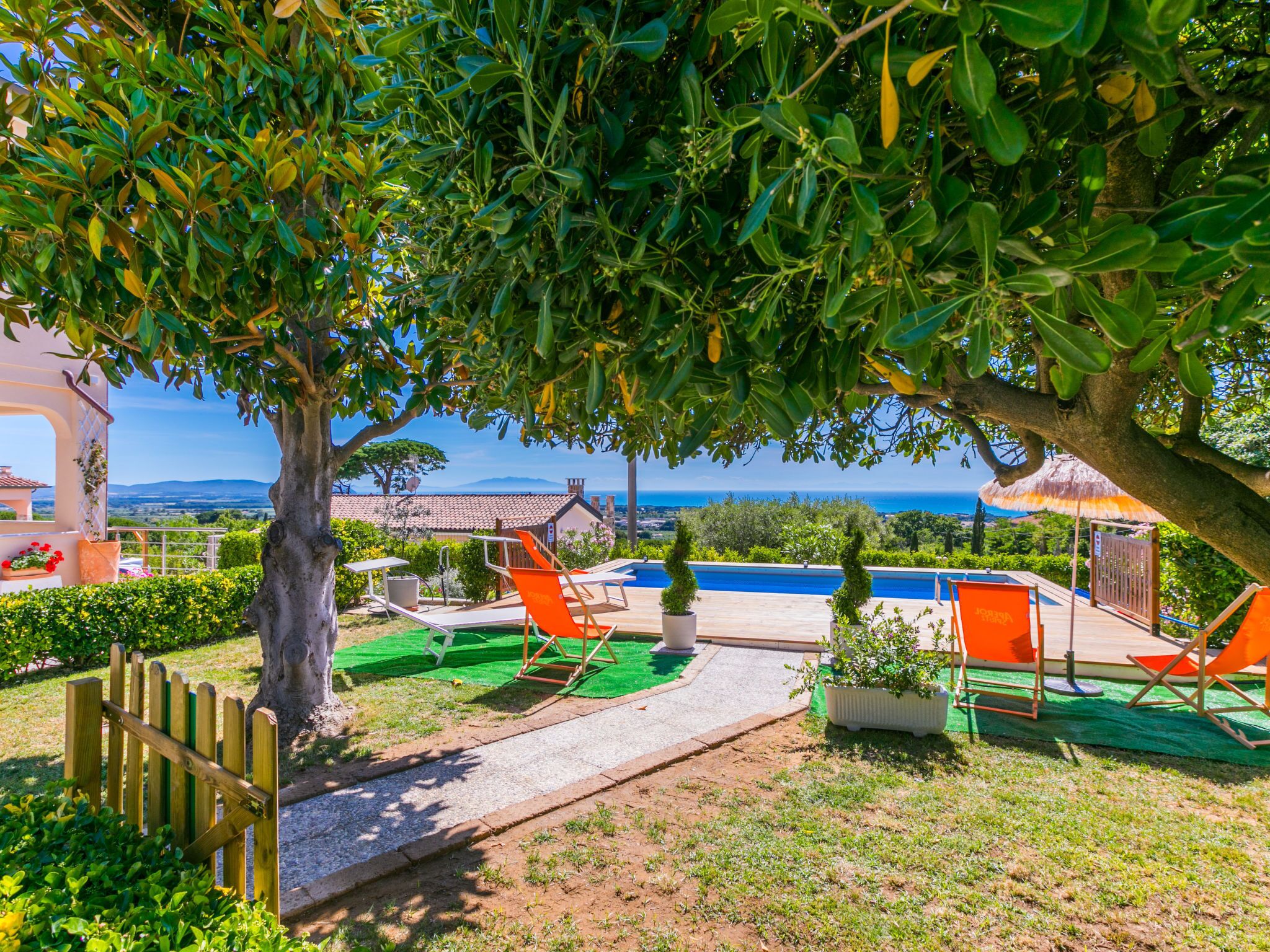 Zona de piscina con sillones reclinables, una pérgola y vista al mar.