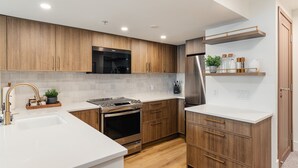 Una cocina moderna con armarios de madera, electrodomésticos de acero inoxidable y una encimera blanca.