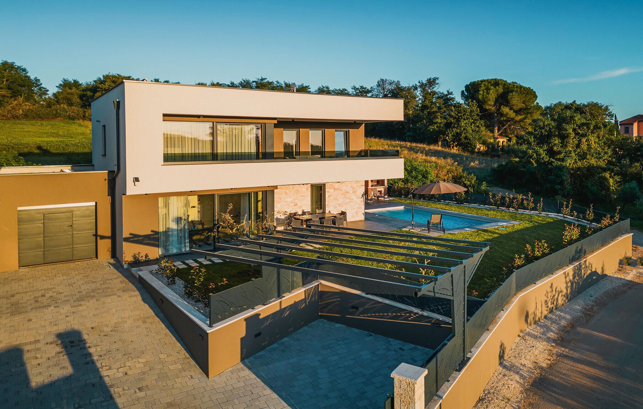 Une maison moderne à deux étages, dotée d’une piscine, d’un espace salon extérieur couvert et d’un jardin bien entretenu.