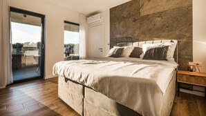A bedroom with a bed, a nightstand, an air conditioning unit, and a view through a glass door. - Amazing home in Kastelir with sauna (Kastelir)