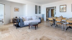 A spacious living area with a sofa, coffee table, and dining table set up. - Les Astérides by Interhome (Hyères)