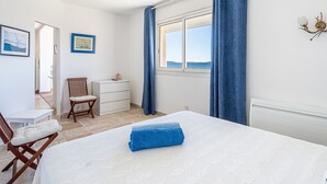 A bedroom with a bed, a chair, a dresser, and a window with a view of the sea. - Les Astérides by Interhome (Hyères)