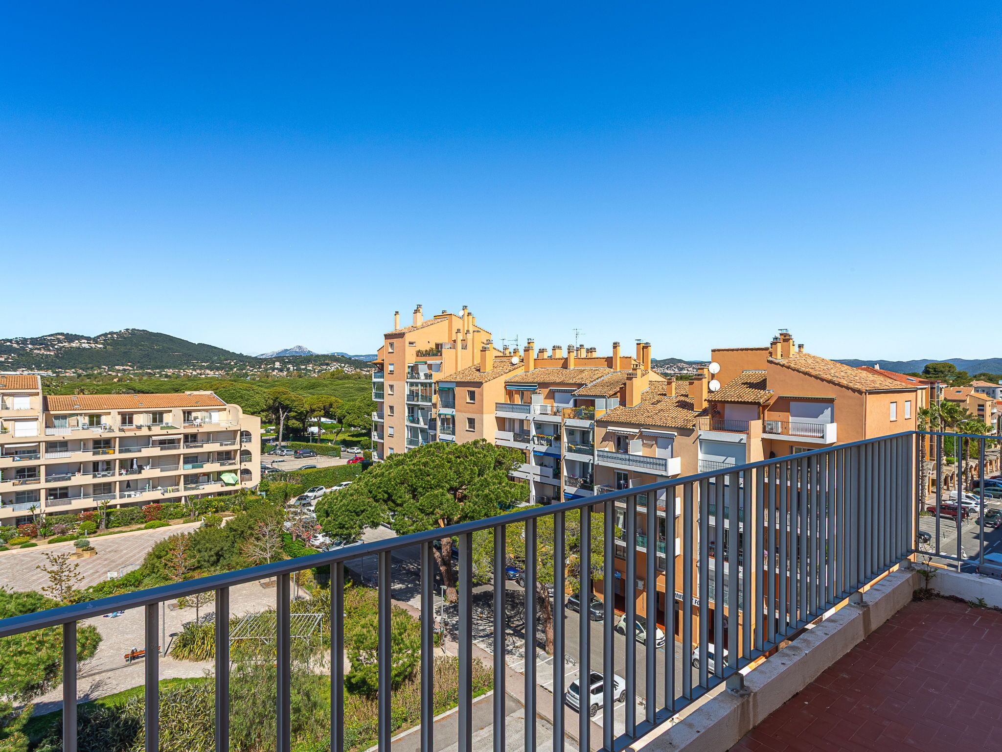 A residential area with multi-story buildings, a clear sky, and a distant mountain range.