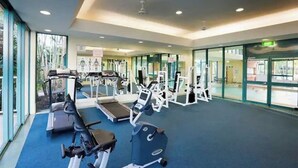 Ein Fitnessstudio mit Laufbändern, Kraftgeräten und einem blauen Teppich.
