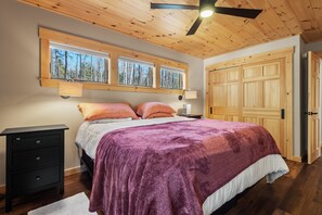 Une chambre à coucher avec un lit, un plafond en bois, des fenêtres et une porte.