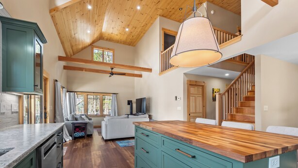 Una cocina amplia con vigas de madera, una isla grande y un comedor con una escalera.