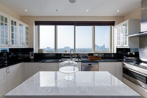A modern kitchen with a large island, stainless steel appliances, and a view of the city.