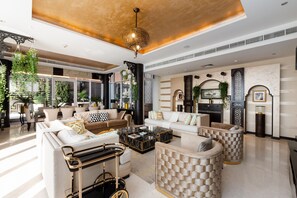 A spacious living area with a large sofa set, a coffee table, and a decorative wall unit.