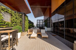 Un patio al aire libre con mobiliario de mimbre, una zona de estar y una pared vertical cubierta de jardín.