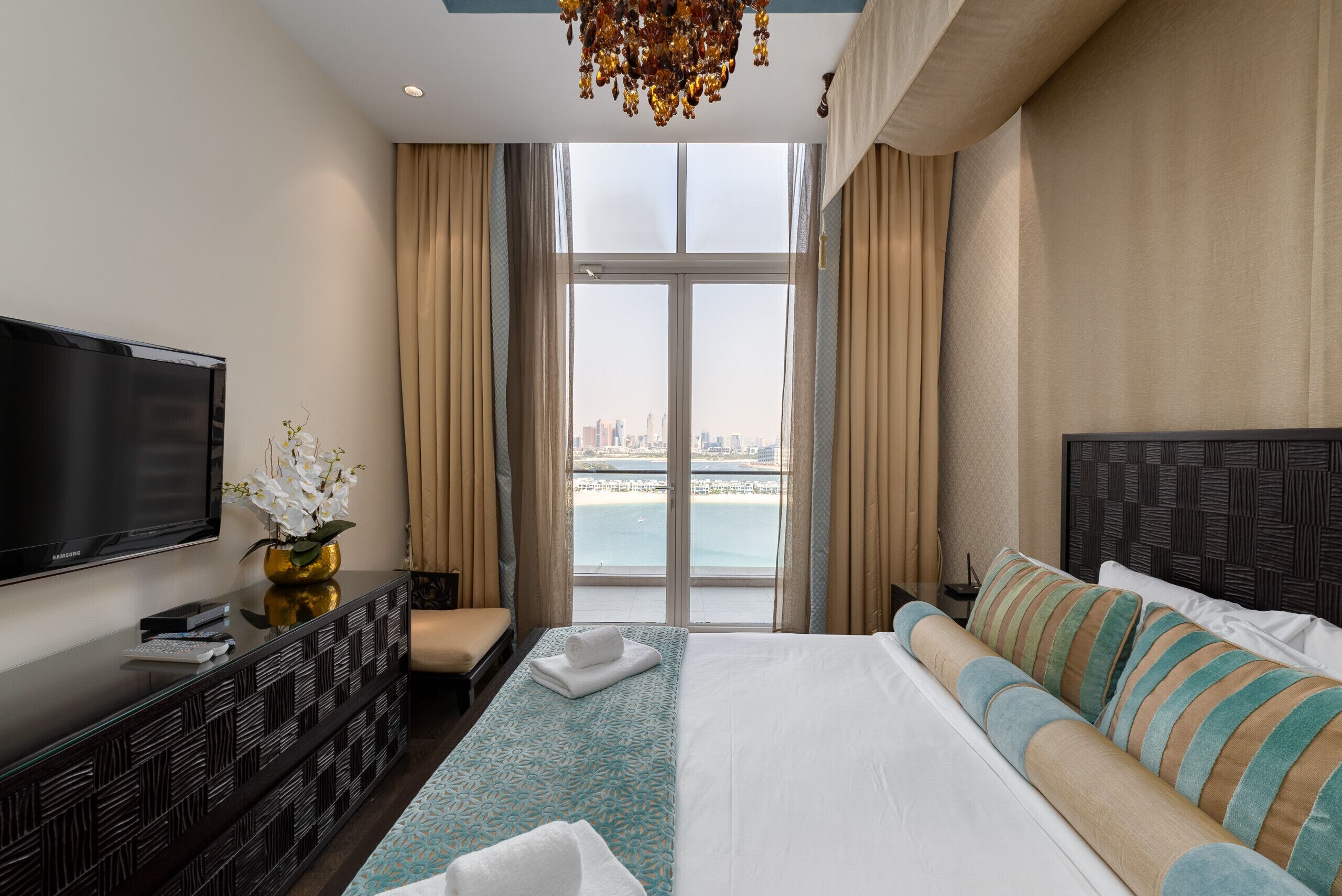 Ein modernes Hotelzimmer mit einem großen Bett, einer Couch, einem Fernseher und Blick auf die Stadt und das Wasser.