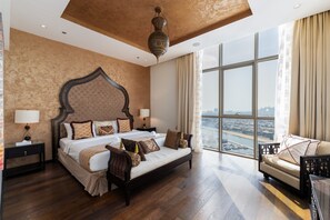 Une chambre spacieuse avec un grand lit, un canapé et une vue sur le paysage urbain, grâce à de grandes fenêtres.