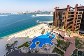 Un complexe hôtelier doté d’une grande piscine, d’une plage et offrant une vue sur le paysage urbain.