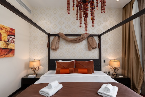 A hotel room with a large bed, two bedside tables with lamps, a decorative headboard, and a hanging ornament.