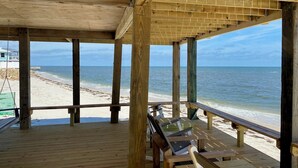 Una terraza de madera con bancos que da vista a una playa.