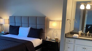 Hotelkamer met een bed, nachtkastjes, een badkamer met een wastafel, spiegel en kastjes.