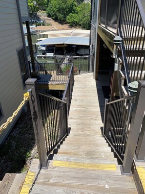 Stairs lead to a deck overlooking a body of water and a dock with boats.
