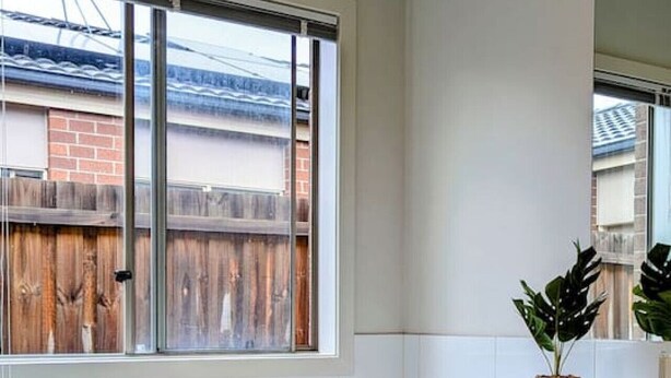 A modern bathroom with a freestanding bathtub, a large window, and a wooden fence visible through the window. - Spacious home near Bellarine Peninsula Trail (Curlewis)