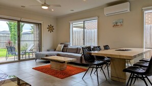 A spacious living area with a sofa, coffee table, and dining table. - Spacious home near Bellarine Peninsula Trail (Curlewis)