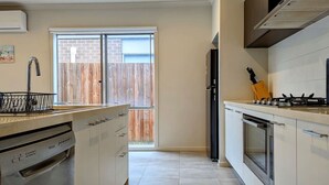 A modern kitchen with a dishwasher, oven, and gas stove. - Spacious home near Bellarine Peninsula Trail (Curlewis)