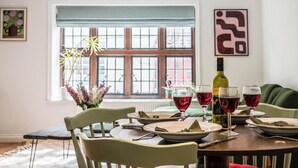 A dining area with a table set for four, a bottle of wine, and glasses of red wine. - 57A Thoroughfare, Woodbridge (Woodbridge)