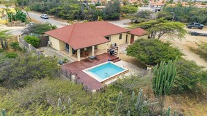 Una casa circondata da cactus e vegetazione, con una piscina.