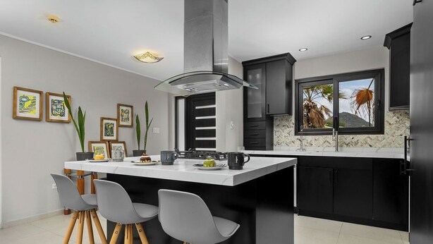 Una cucina moderna con isola centrale, sgabelli da bar e un'ampia finestra vista.