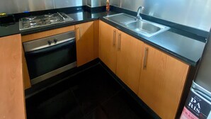 Une cuisine de taille réduite, dotée d’armoires en bois, d’une cuisinière en acier inoxydable et d’un évier.