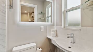 A modern bathroom with a toilet, sink, and glass shelves.