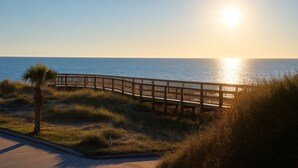 A wooden boardwalk leading to a beach with the sun setting in the background. - Luxury Studio • Steps to Beach • Kitchenette • Outdoor Seating (Fernandina Beach)