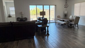 Un salón amplio con un sofá marrón oscuro, una mesa de centro y un comedor con mesa y sillas.