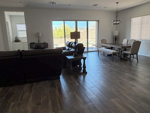 A spacious living room with a dark brown sofa, a coffee table, and a dining area with a table and chairs.
