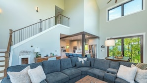 A spacious living area with a sectional sofa, a wooden coffee table, and a staircase leading to an upper level.