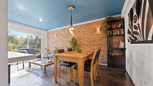 Un coin repas avec un mur en briques, une table en bois et des chaises. On y trouve également une bibliothèque remplie de livres et un élément décoratif mural.