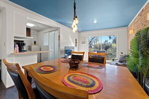 A dining area with a wooden table, chairs, and a ceiling light fixture.