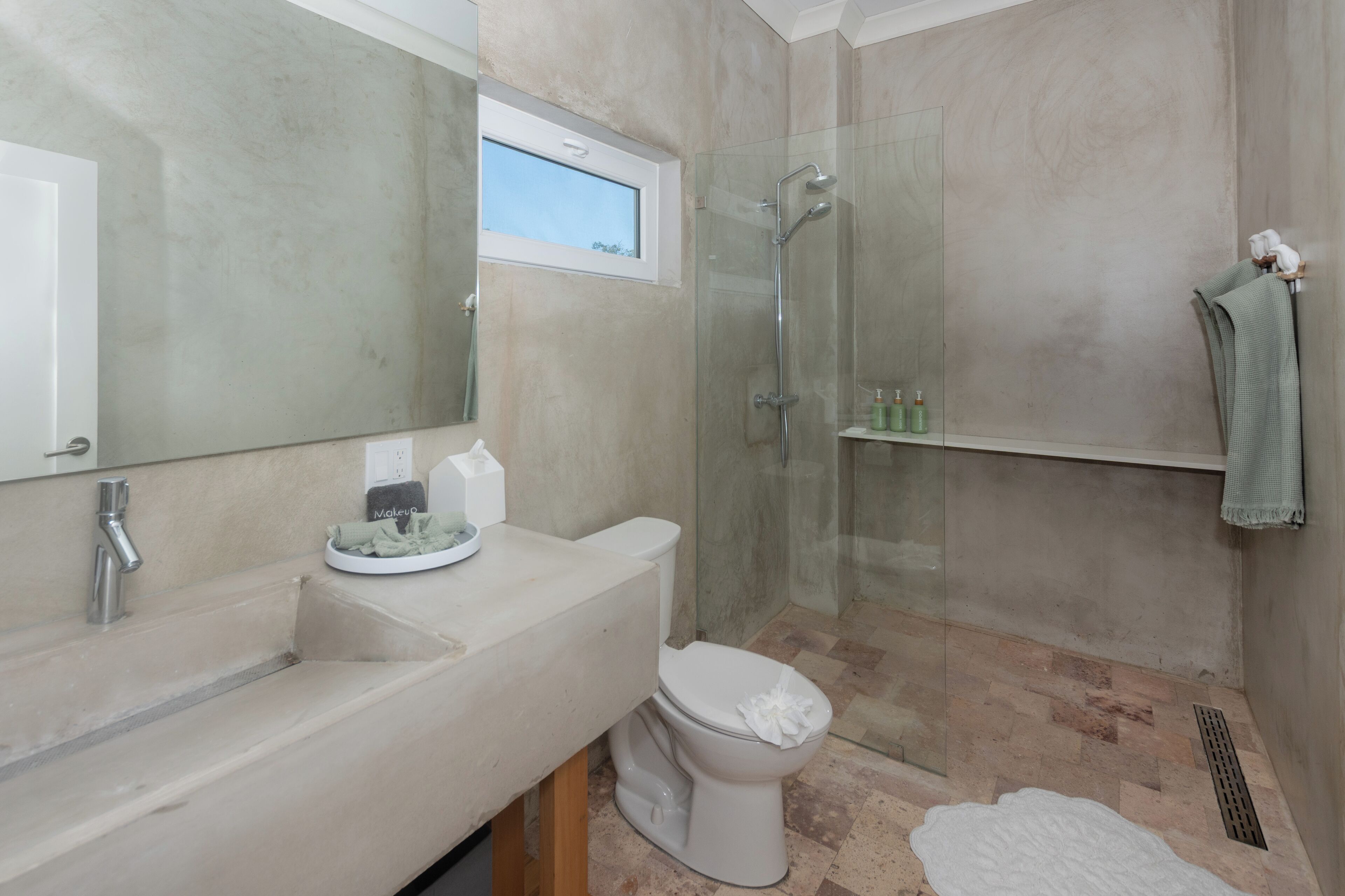 Un baño moderno con un espejo grande, un inodoro, una ducha y un lavamanos.