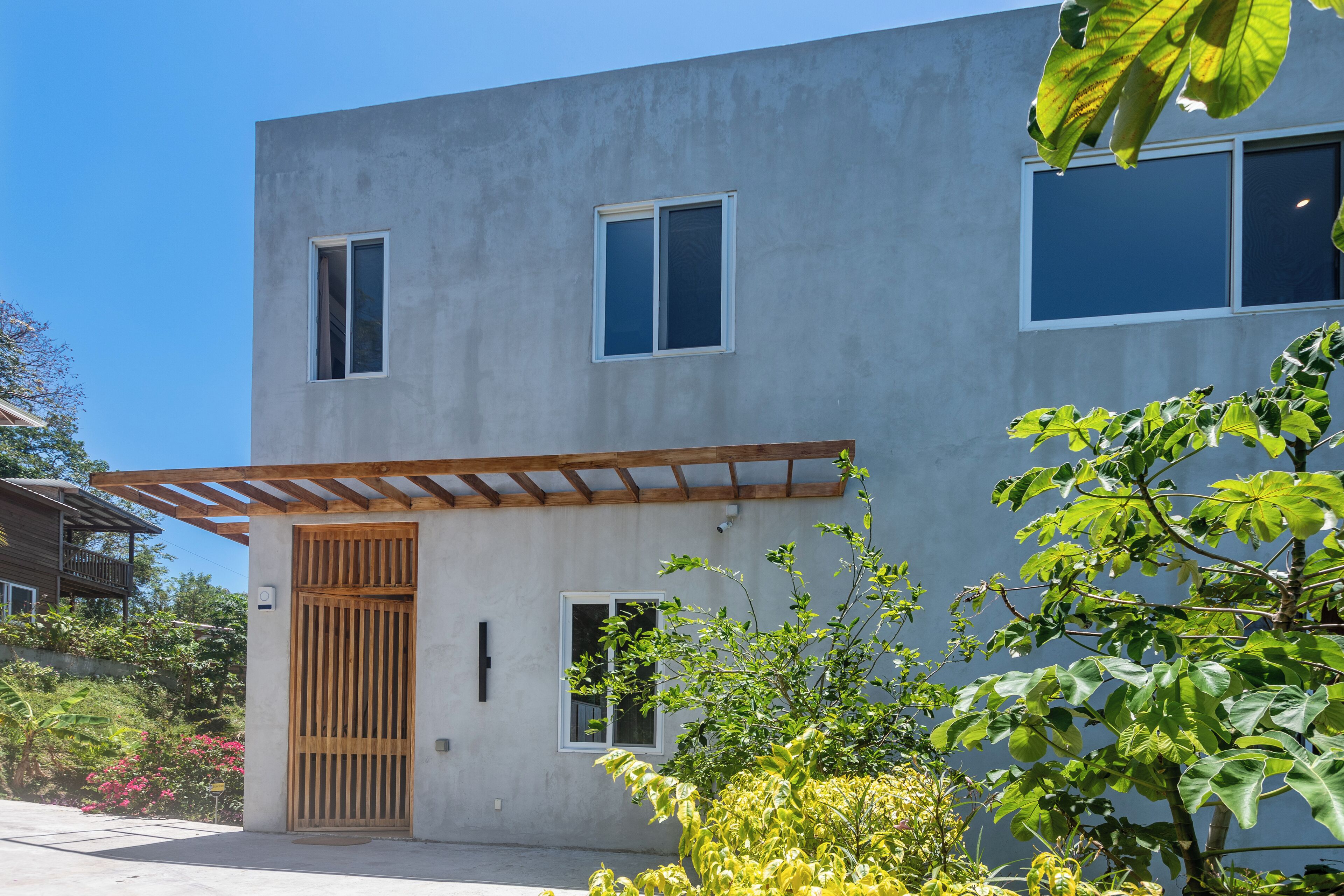 Un bâtiment moderne à deux étages, doté d’une façade en béton, d’une porte en bois et d’une petite fenêtre.