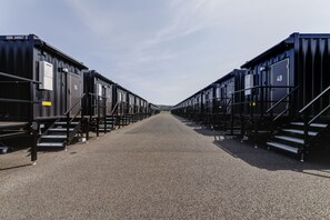 Une rangée de wagons de train noirs, portant des numéros, sous un ciel dégagé.