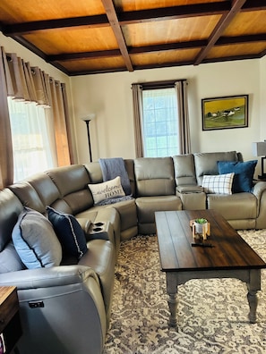 A living room with a sectional sofa, a wooden coffee table, and a patterned rug. - Charming Farmhouse 10 acres near MidOH Race, Clear Fork & Mt Gilead State Parks (Galion)