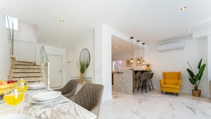 A modern kitchen with marble countertops, a dining area with a marble table, and a bright yellow armchair. - Peaceful Lux, 3 Bed townhouse 10 min to the Beach REF016 (Mijas Costa)