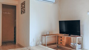 Minimalistinen olohuone, jossa on puinen työpöytä, litteänäyttöinen televisio ja lasinen sohvapöytä.