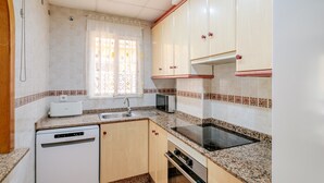 A kitchen with a dishwasher, microwave, stove, and sink.