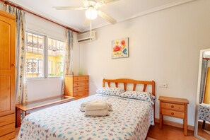 A bedroom with a bed, wooden nightstand, and a ceiling fan. - Apartment 'Pretty Bungalow' with Mountain View, Wi-Fi and Air Conditioning (Santa Pola)