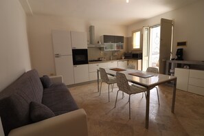 A compact living space with a kitchenette, dining area, and a sofa.