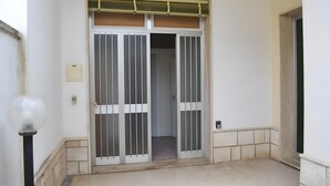 A doorway with a metal gate, a light fixture, and a tiled floor.