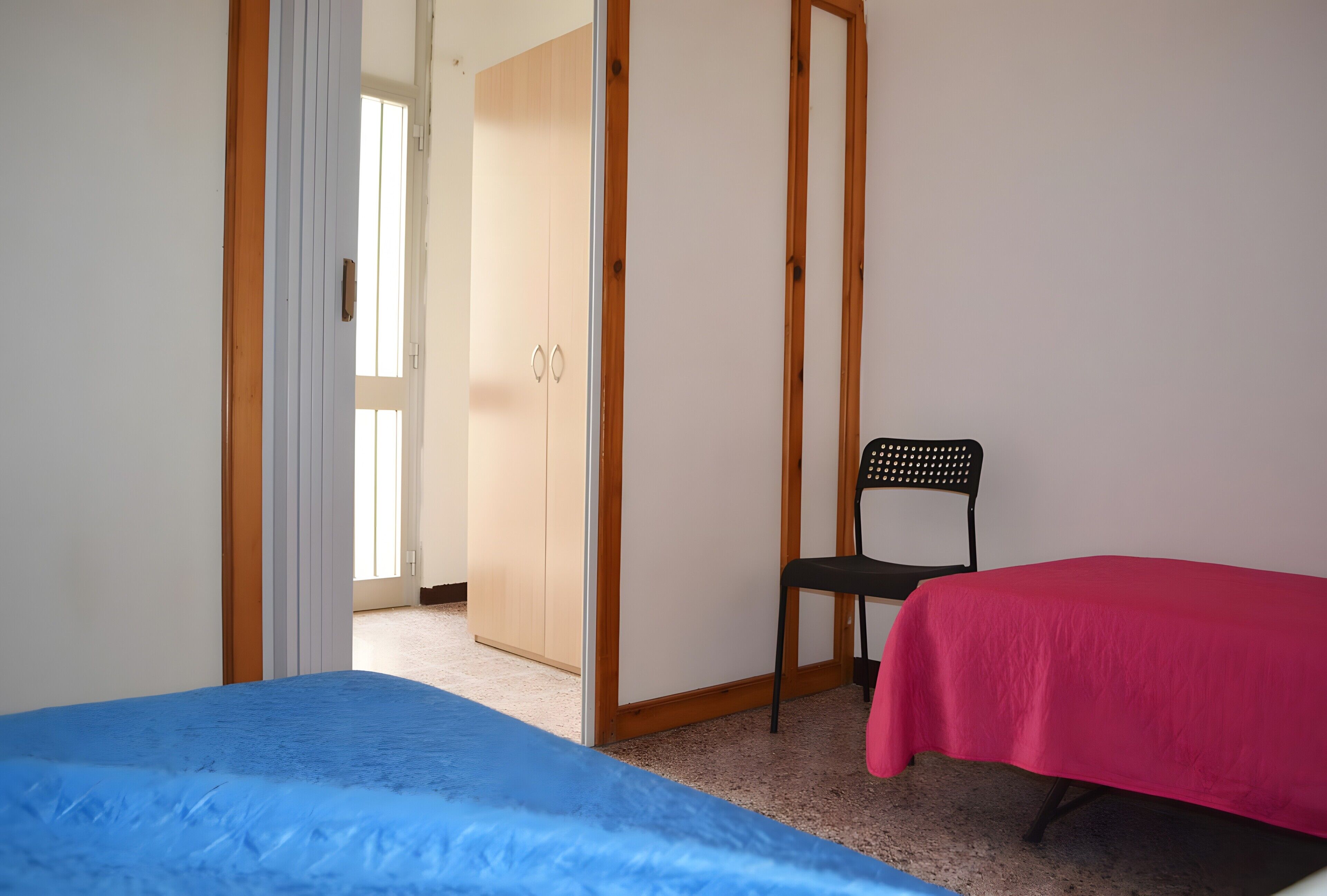 A bedroom with a bed, a chair, and a wardrobe.