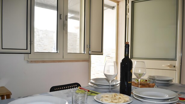 A dining table set with plates, glasses, and a bottle, with a window in the background.