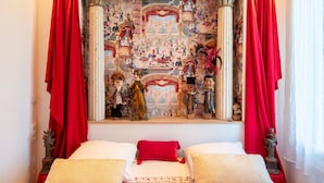 Een slaapkamer met een groot raam, rode gordijnen en een muurschildering.