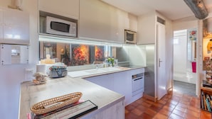 Een moderne keuken met witte kastjes, een magnetron, een broodrooster en een spoelbak.