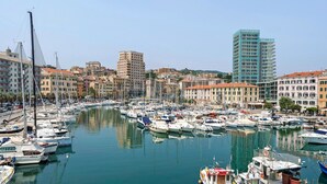 A marina filled with various boats, surrounded by buildings with a mix of architectural styles. - Cruise Apartment with Private Terrace, Balcony, and Wi-Fi (Savona)